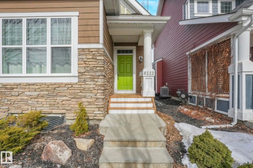 The property features a lime green front door, a stone facade, and a covered porch with white columns - 8112 Summerside Grande Boulevard, Edmonton, AB - Outdoor