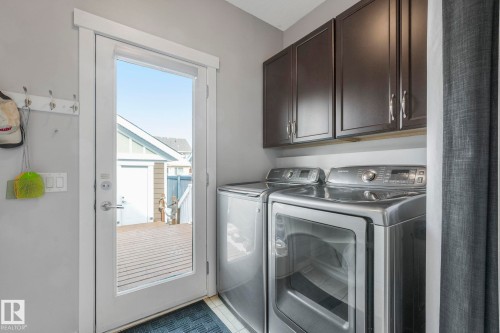 The laundry area features dark cabinetry and a glass-paneled door, providing direct outdoor access to a deck - 8112 Summerside Grande Boulevard, Edmonton, AB - Indoor Photo Showing Laundry Room