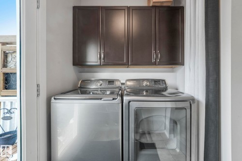 The laundry area features dark cabinetry and stainless steel appliances - 8112 Summerside Grande Boulevard, Edmonton, AB - Indoor Photo Showing Laundry Room
