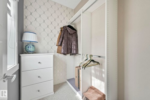 The property features a closet with built-in shelving, hanging rods, and a patterned accent wall - 8112 Summerside Grande Boulevard, Edmonton, AB - Indoor