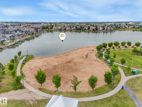 Aerial view showcasing a sandy beach area with volleyball nets, surrounded by green spaces and pathways - 8112 Summerside Grande Boulevard, Edmonton, AB - Outdoor With Body Of Water With View