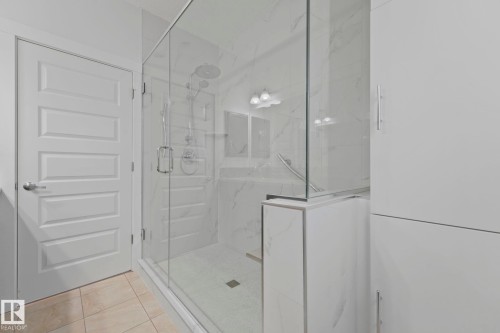 The bathroom features a new spacious glass-enclosed shower with white marble-style tiling and a square drain - 8112 Summerside Grande Boulevard, Edmonton, AB - Indoor Photo Showing Bathroom