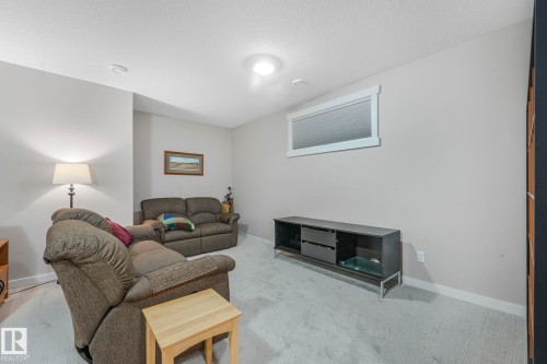 The room features light gray carpeting, neutral wall paint, and a horizontal window with white trim - 8112 Summerside Grande Boulevard, Edmonton, AB - Indoor Photo Showing Other Room