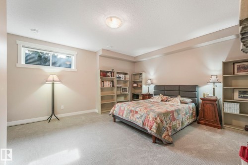 This inviting room features soft carpeting, a window with blinds, and built-in shelving, offering both comfort and practicality - 8112 Summerside Grande Boulevard, Edmonton, AB - Indoor Photo Showing Bedroom