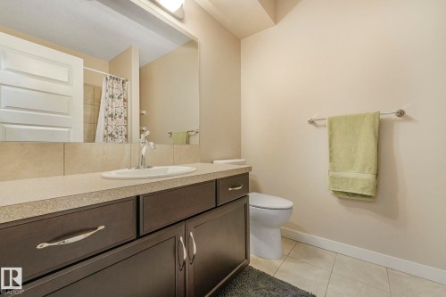 Bathroom with a vanity featuring a light-colored countertop, a single sink, and dark cabinetry with silver-toned hardware - 8112 Summerside Grande Boulevard, Edmonton, AB - Indoor Photo Showing Bathroom