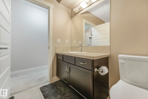 Bathroom featuring a dark wood vanity with a light-colored countertop, a white toilet, and a mirror with overhead lighting - 8112 Summerside Grande Boulevard, Edmonton, AB - Indoor Photo Showing Bathroom