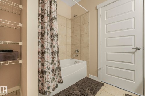 Bathroom featuring a bathtub with tiled surround, shower fixture, and a white paneled door - 8112 Summerside Grande Boulevard, Edmonton, AB - Indoor Photo Showing Bathroom