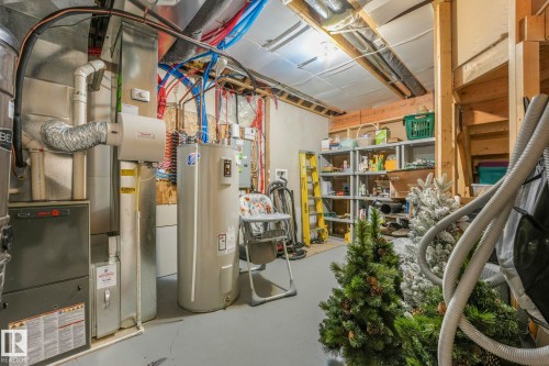 The utility area features a water heater, furnace, and exposed overhead pipes - 8112 Summerside Grande Boulevard, Edmonton, AB - Indoor