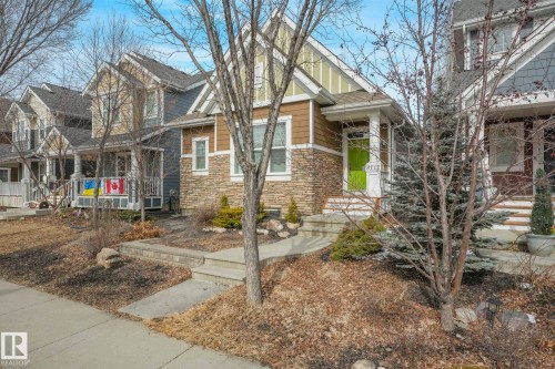 The property features a stone and siding exterior, a front porch, and a vibrant green front door - 8112 Summerside Grande Boulevard, Edmonton, AB - Outdoor With Facade