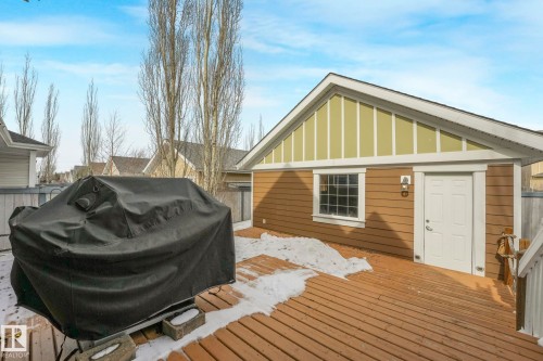 The property features a brown-sided exterior with a white-trimmed window and door, and a light green gable accent - 8112 Summerside Grande Boulevard, Edmonton, AB - Outdoor With Deck Patio Veranda With Exterior