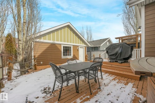 The property features a wood deck with a dining set, an exterior structure with brown siding and a window, and a wooden fence - 8112 Summerside Grande Boulevard, Edmonton, AB - Outdoor With Deck Patio Veranda With Exterior