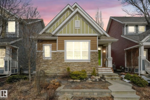 The property features a stone and siding exterior, a front porch with white columns, and an inviting entry with a green door - 8112 Summerside Grande Boulevard, Edmonton, AB - Outdoor With Facade