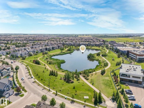 Aerial view showcasing the property's surrounding area, featuring a serene lake with walking paths, lush green spaces, and nearby residential properties - 8112 Summerside Grande Boulevard, Edmonton, AB - Outdoor With View