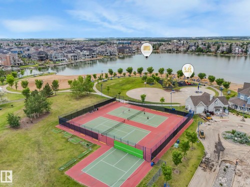 Aerial view showcasing a community with a lake, tennis courts, and a sandy beach area - 8112 Summerside Grande Boulevard, Edmonton, AB - Outdoor With Body Of Water With View