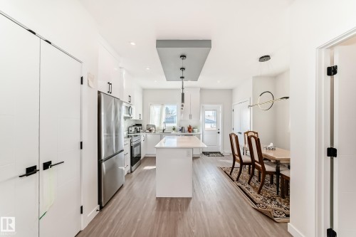 The kitchen features white cabinetry, stainless steel appliances, and a central island with a light- coloured  quartz countertop - 12435 47 Street Nw, Edmonton, AB - Indoor Photo Showing Kitchen With Upgraded Kitchen