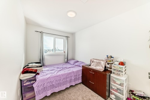 Bedroom two-This room features light-colored walls and carpeting, a window with grey curtains, and a ceiling light fixture - 12435 47 Street Nw, Edmonton, AB - Indoor Photo Showing Bedroom