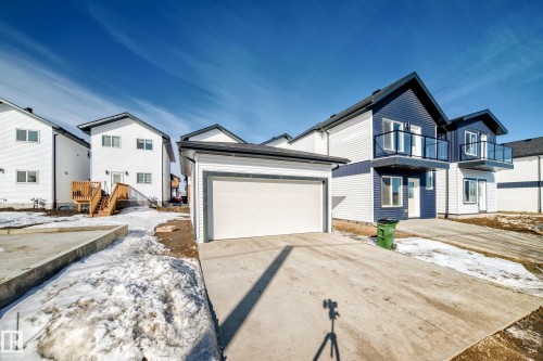 The property features a white garage with a concrete driveway and blue and white exterior siding - 12435 47 Street Nw, Edmonton, AB - Outdoor