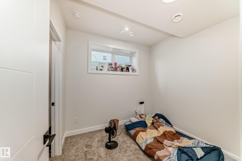 Basement bedroom one of two.The room features a window providing natural light, recessed ceiling lights, and carpeted flooring - 12435 47 Street Nw, Edmonton, AB - Indoor