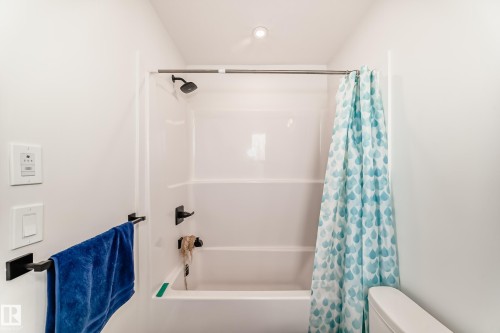 Bathroom featuring a white shower and bathtub combination with matte black fixtures - 12435 47 Street Nw, Edmonton, AB - Indoor Photo Showing Bathroom