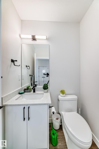 The bathroom features a modern vanity with a white countertop and integrated sink, a toilet, and light-toned flooring - 12435 47 Street Nw, Edmonton, AB - Indoor Photo Showing Bathroom