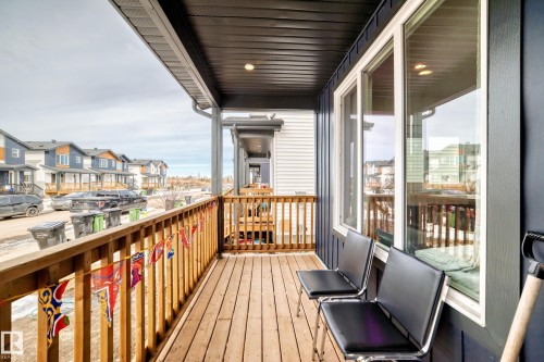 Inviting porch with wood decking, wood railings, and a dark soffit, providing an outdoor living space. - 12435 47 Street Nw, Edmonton, AB - Outdoor With Exterior