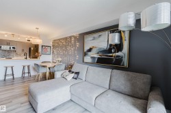This open-concept living space features light wood-look flooring, a kitchen with grey cabinetry and a white countertop, and an integrated dining area - 
