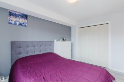 This bedroom features a light grey upholstered headboard, light-toned flooring, and a closet with bi-fold doors - 