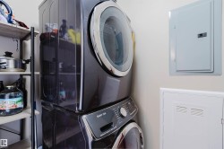 This utility area includes a stacked washer and dryer, along with wall-mounted electrical panels - 