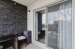 This inviting outdoor space features a stone accent wall, white siding, and a sliding glass door for seamless indoor-outdoor accessibility - 