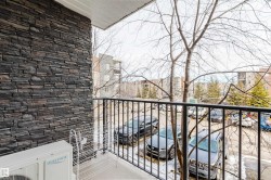 The property features a balcony with a black metal railing, offering views of parked vehicles - 