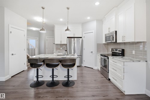 The property features a kitchen with white cabinetry, granite countertops, and stainless steel appliances - 8424 Cushing Court, Edmonton, AB - Indoor Photo Showing Kitchen With Double Sink With Upgraded Kitchen