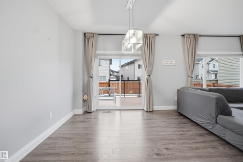 Living area featuring light grey walls, light wood flooring, and a glass sliding door that opens to a deck with a wooden railing - 8424 Cushing Court, Edmonton, AB - Indoor