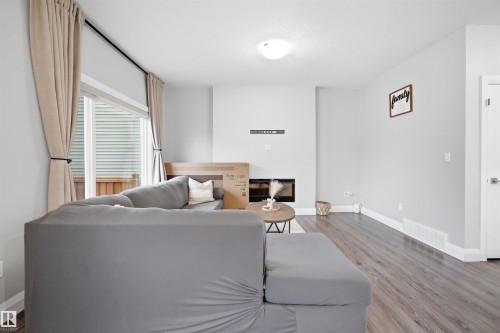 Living room featuring dark wood-style flooring, a large window with blinds and drapes, and a fireplace - 8424 Cushing Court, Edmonton, AB - Indoor Photo Showing Living Room