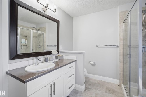 Bathroom featuring a vanity with a white oval sink, dark countertop, and white cabinetry - 8424 Cushing Court, Edmonton, AB - Indoor Photo Showing Bathroom