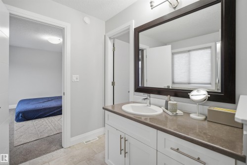 The bathroom features a vanity with a countertop, an under-mount sink, and a large mirror - 8424 Cushing Court, Edmonton, AB - Indoor Photo Showing Bathroom