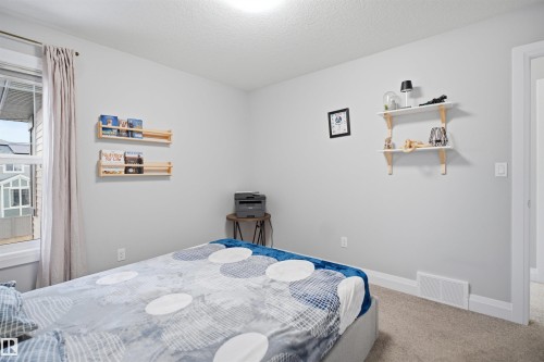 Bedroom featuring light gray walls, carpeted flooring, a window with curtains, and built-in wall shelving - 8424 Cushing Court, Edmonton, AB - Indoor Photo Showing Bedroom