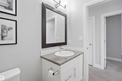 Bathroom featuring a modern vanity with a white sink, a dark framed mirror, and light gray walls - 8424 Cushing Court, Edmonton, AB - Indoor Photo Showing Bathroom