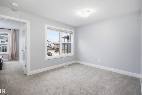 The room features light gray carpeting, neutral wall paint, and a window with a view of the surrounding properties - 8424 Cushing Court, Edmonton, AB - Indoor Photo Showing Other Room