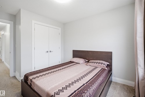 This room features a neutral color palette, carpeting, and a closet with double doors - 8424 Cushing Court, Edmonton, AB - Indoor Photo Showing Bedroom
