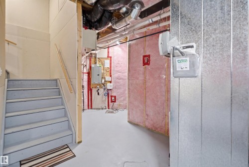 The property features a staircase with a wooden handrail, leading to a utility area with exposed ductwork and insulation - 8424 Cushing Court, Edmonton, AB - Indoor Photo Showing Other Room