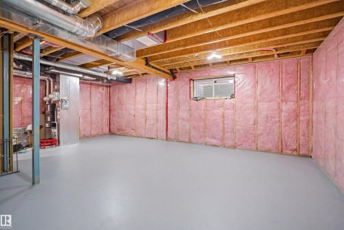 Unfinished space featuring exposed wooden ceiling joists, pink insulation on the walls, and a window - 8424 Cushing Court, Edmonton, AB - Indoor Photo Showing Basement