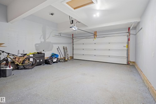 The property features a garage with a light gray painted finish on the walls and ceiling, a gray speckled floor, and an overhead garage door - 8424 Cushing Court, Edmonton, AB - Indoor Photo Showing Garage