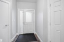 The property features a front entry with a white door, a sidelight, and wood-look flooring - 8424 Cushing Court, Edmonton, AB  - Indoor Photo Showing Other Room 