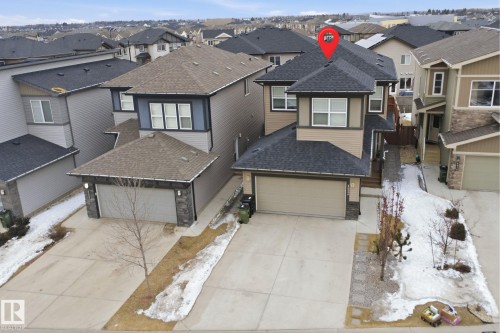 The property features a two-story design with an attached garage, a paved driveway, and a front yard with some landscaping elements - 8424 Cushing Court, Edmonton, AB - Outdoor With Facade