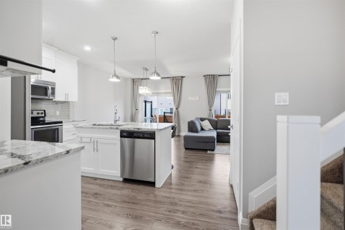 The kitchen features white cabinetry, granite countertops, stainless steel appliances, and pendant lighting - 8424 Cushing Court, Edmonton, AB - Indoor Photo Showing Kitchen With Upgraded Kitchen