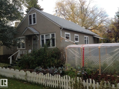 The property features a stucco exterior, a sloped roof, and a front porch with white railings - 9828 78 Avenue, Edmonton, AB 