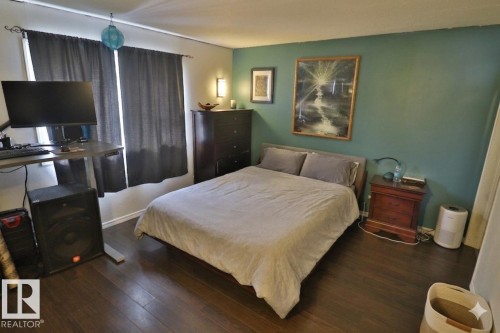 This room features dark hardwood flooring, a green accent wall, and a window with dark curtains - 11 Willow Park Estates, Leduc, AB - Indoor Photo Showing Bedroom