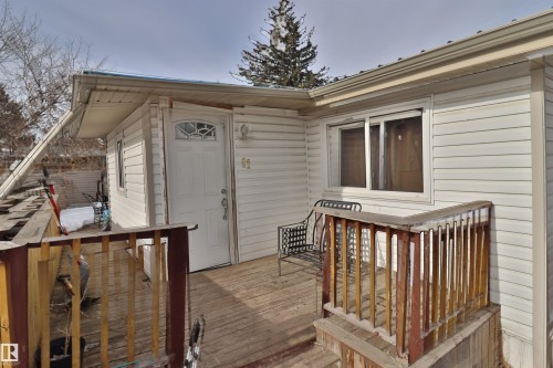 The property features white siding and a wooden deck with railing - 11 Willow Park Estates, Leduc, AB - Outdoor With Exterior