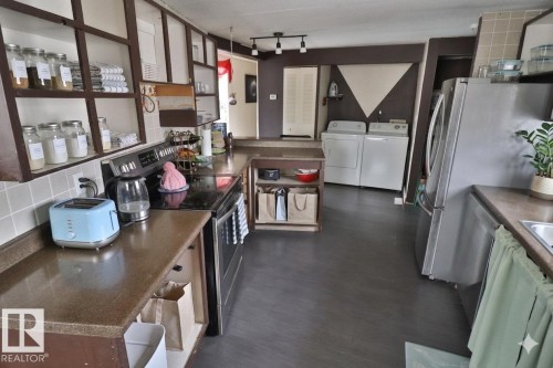 The kitchen features a stainless steel refrigerator, an electric range, and ample countertop space - 11 Willow Park Estates, Leduc, AB - Indoor Photo Showing Kitchen