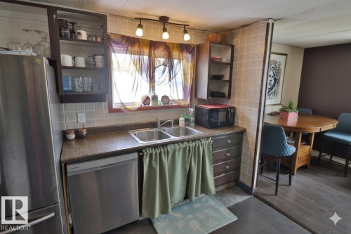 The kitchen features a double stainless steel sink, a stainless steel dishwasher, and a refrigerator - 11 Willow Park Estates, Leduc, AB - Indoor Photo Showing Kitchen With Double Sink